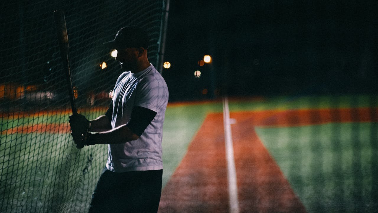 Silhouette of baseball player practicing batting at night on the field.
